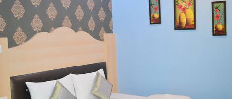 Un dormitorio con una cama, un cabecero y tres cuadros en la pared.