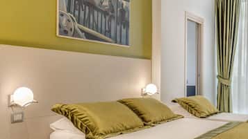 Una camera d'albergo con un letto grande, due abat-jour, un quadro appeso al muro e una finestra con tende.