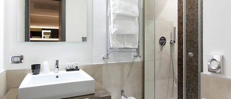 Une salle de bain moderne dotée d’un grand lavabo, d’un bidet et d’une douche à parois de verre.