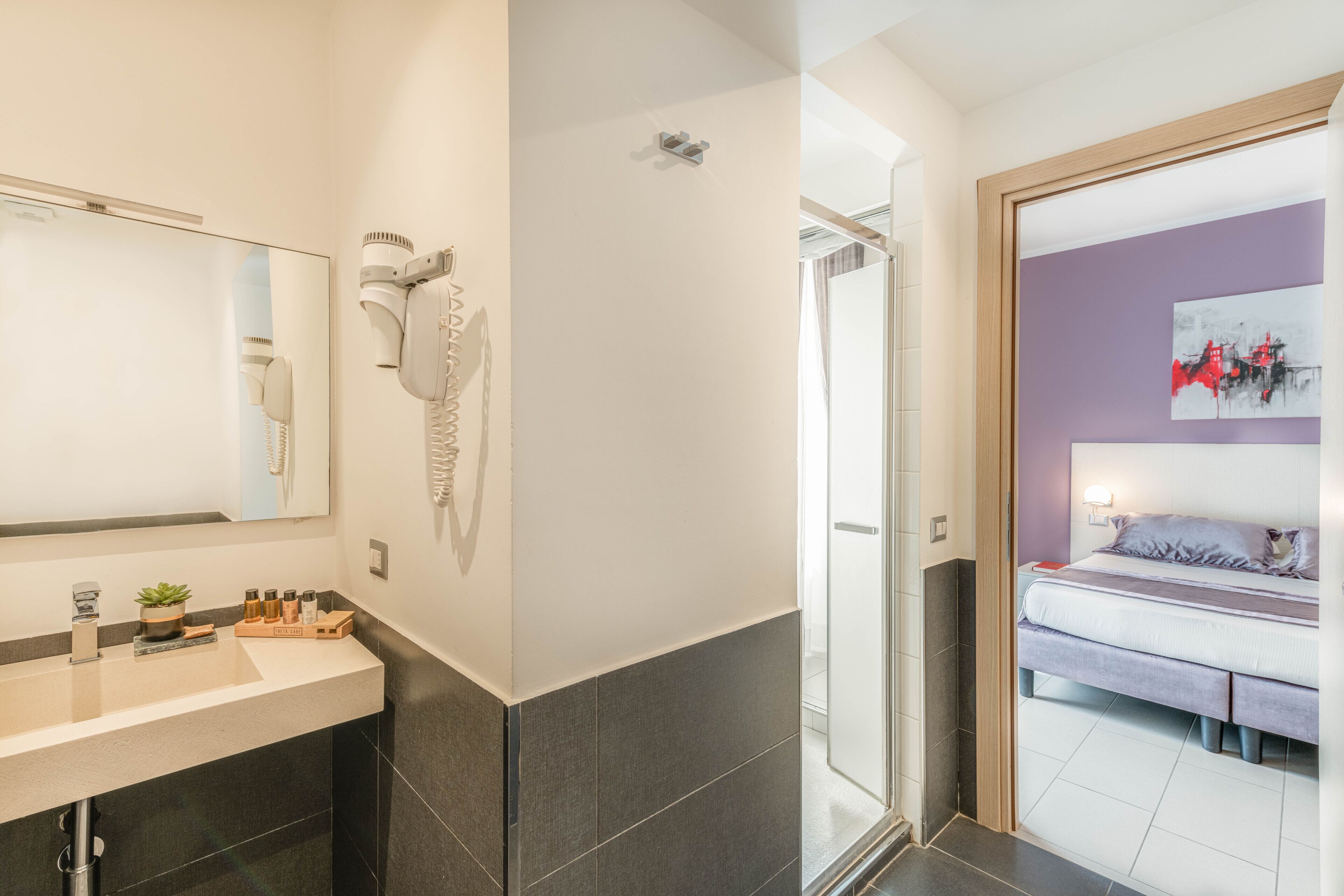 A modern bathroom with a large mirror, hairdryer, and a shower area.
