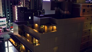 A modern building with multiple balconies and outdoor lighting, surrounded by other buildings. - Busan Amare Hotel (Busan)