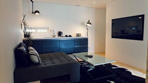A modern living room with a glass coffee table, a grey sofa, a black and white rug, and a flat-screen TV mounted on the wall. - Busan Amare Hotel (Busan)