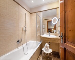 Un baño moderno con bañera, ducha, tocador con espejo y perchero para toallas.