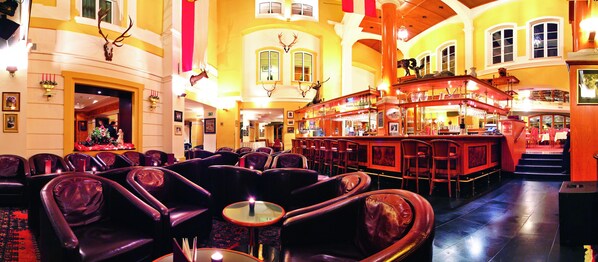A bar area with leather seating and a bar counter. - Villa Orania (Bad Gastein)