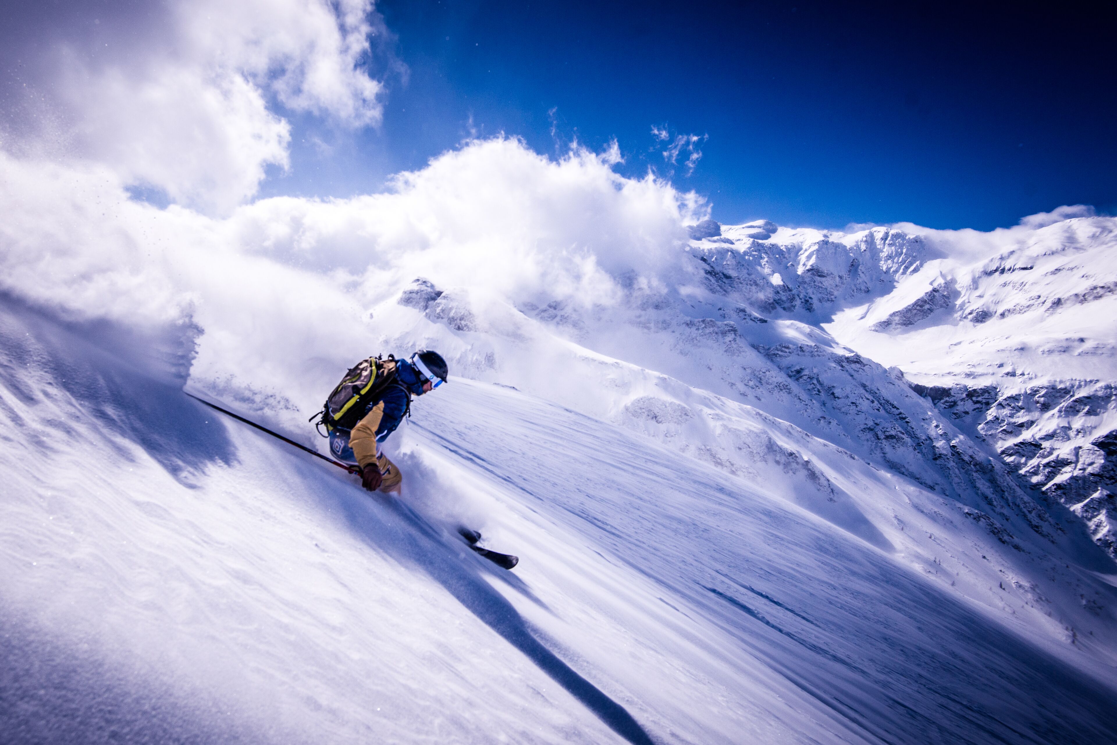 A snowboarder descending a steep, snow-covered mountain slope.