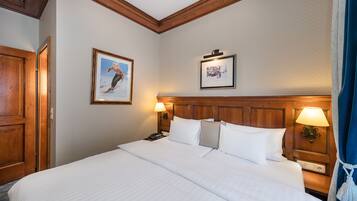 A hotel room with a large bed, wooden headboard, two bedside lamps, and framed pictures on the walls.