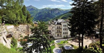 Un hotel con un patio central, rodeado de exuberante vegetación y montañas al fondo.