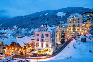 Um hotel com vários andares, paisagem coberta de neve e uma montanha ao fundo.