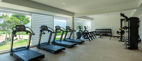 Un gimnasio con cintas de correr, máquinas de pesas y mancuernas.