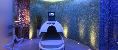 A modern spa room with a massage chair, a digital display, and mosaic walls.