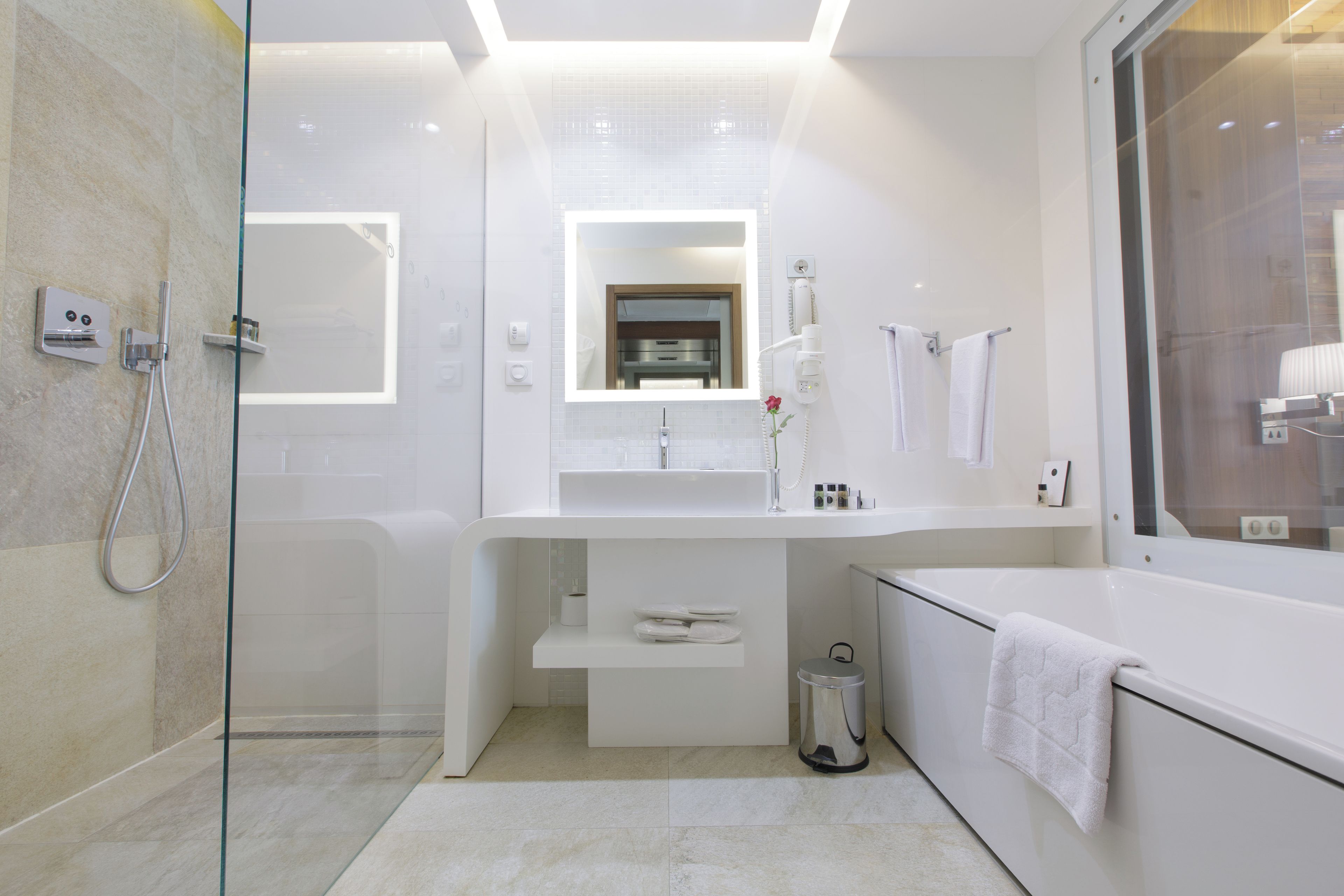 A modern bathroom with a glass-enclosed shower, a white vanity with a mirror, and a bathtub.
