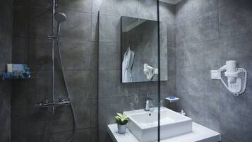 A modern bathroom with a large mirror, a white sink, and a handheld showerhead.