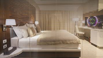 Quarto moderno com cama grande, mesa de cabeceira e luminária fixada na parede.