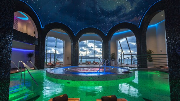 A luxurious indoor pool area with a central hot tub, surrounded by arched walkways and lounge chairs, offering a view of the sea. - La Cigale Tabarka Hôtel Spa & Golf (Tabarka)