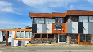 A modern hotel with a prominent logo, large windows, and a stone facade. - Waterways, A Boutique Hotel (Powell River)