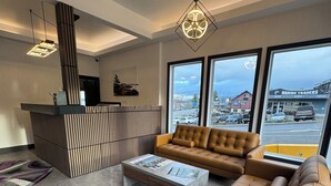 A modern living room with a sofa, coffee table, and a reception desk. - Waterways, A Boutique Hotel (Powell River)