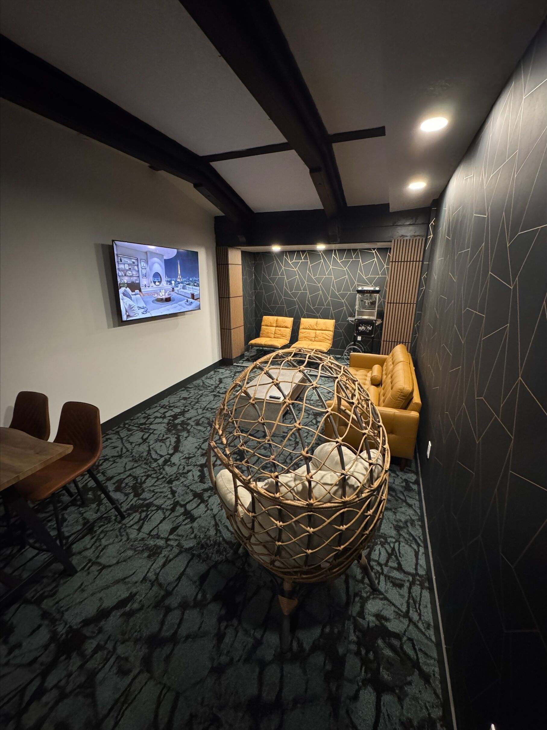 A modern living room with a large screen, comfortable seating, and a unique spherical chair.
