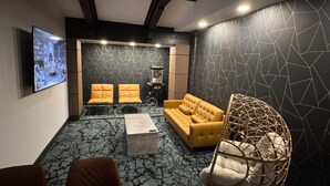 A modern living room with a sofa, chairs, a coffee table, and a TV mounted on the wall. - Waterways, A Boutique Hotel (Powell River)