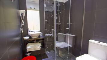 Een moderne badkamer met een douchecabine van glas, een witte wastafel en een rood toilet.