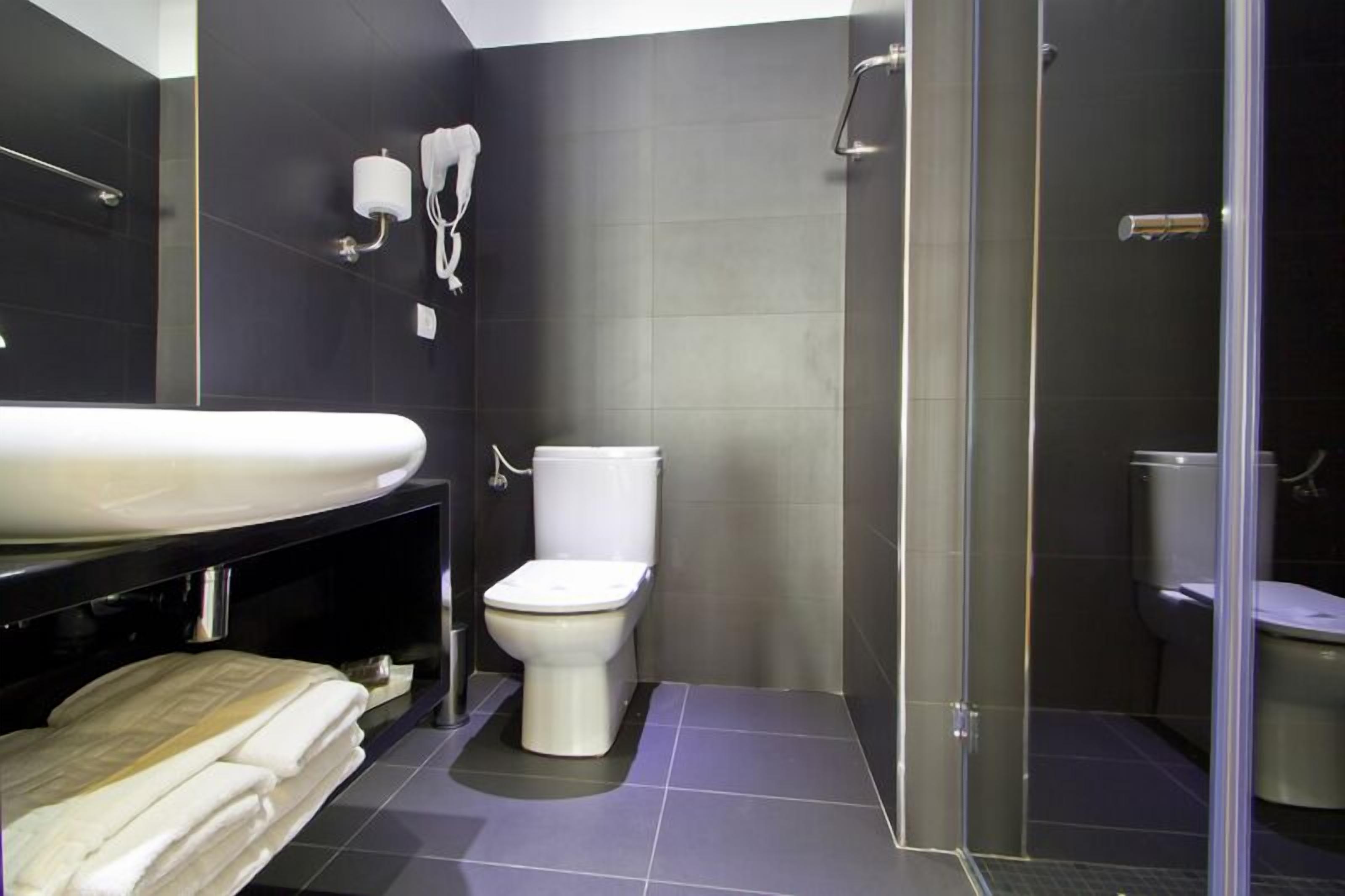 Un baño moderno con un lavamanos grande, un inodoro y una zona de ducha con mampara de vidrio.