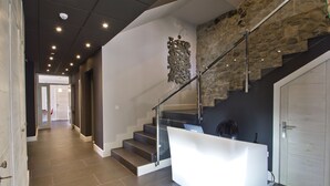 Een modern interieur met een trap, een receptiebalie en een stenen muur.
