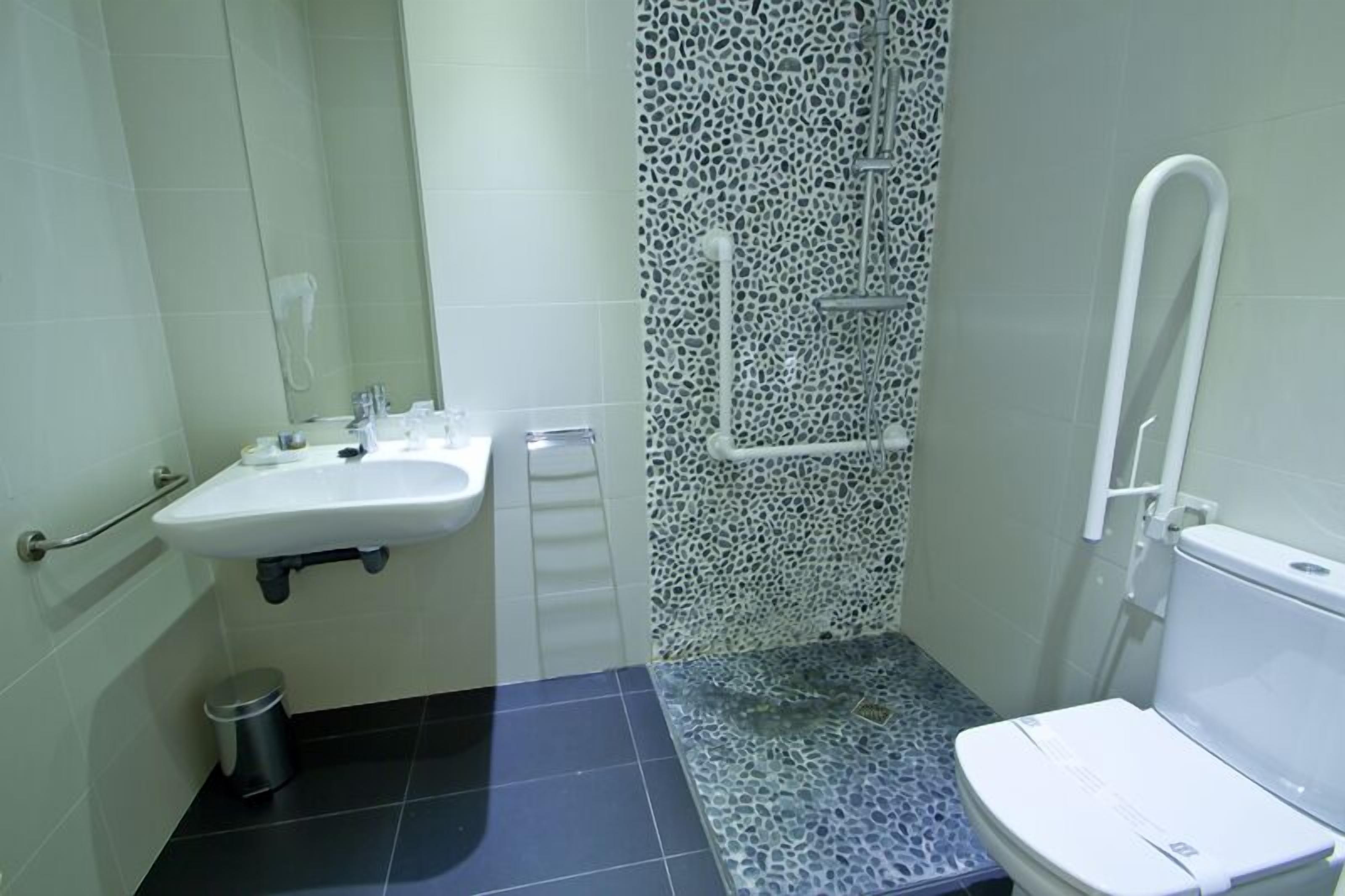 A small bathroom with a white sink, a toilet, and a shower area.