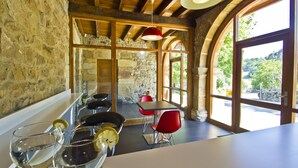 Een rustiek interieur met stenen muren, houten balken en grote gewelfde ramen die uitzicht bieden op het omliggende landschap.