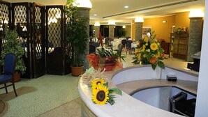 A reception area with a counter, potted plants, and a seating area. - La Bruca Resort (Scalea)