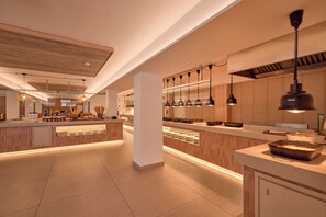 Una cocina moderna con una isla central, iluminación colgante y una amplia variedad de utensilios de cocina.