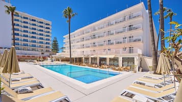 Relax by the pool surrounded by palm trees and lounge chairs.
