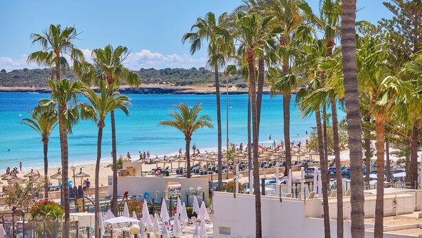 A beach resort with palm trees, a pool area, and a view of the sea. - Universal Hotel Bikini (Sant Llorenc des Cardassar)