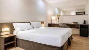 A hotel room with a large bed, bedside tables, a desk, and a chair.