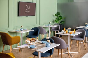A modern dining area with green walls, multiple tables, and chairs.