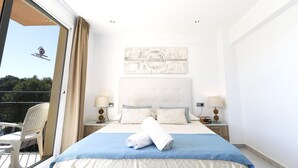 A hotel room with a bed, two bedside tables, a window with curtains, a view of the outdoors, and a small balcony with a chair. - Hotel Gabarda (Calvia)