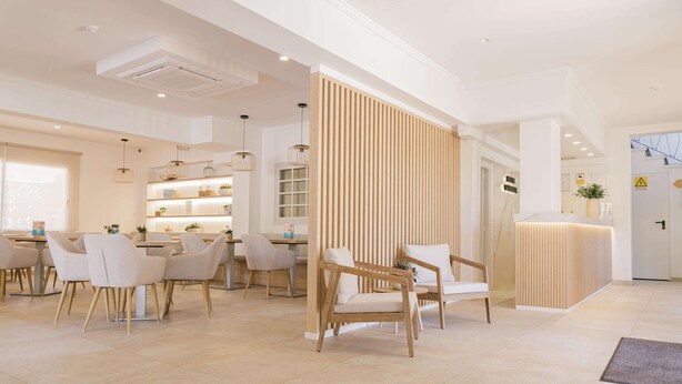 A modern hotel lobby with a reception desk, seating area, and a wooden partition. - Hotel Gabarda (Calvia)