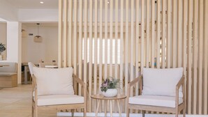 A modern interior with two wooden chairs, a small round table with a plant, and a vertical wooden panel. - Hotel Gabarda (Calvia)