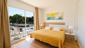 A hotel room with a large bed, a balcony with a view of the street, and a painting on the wall. - Hotel Gabarda (Calvia)