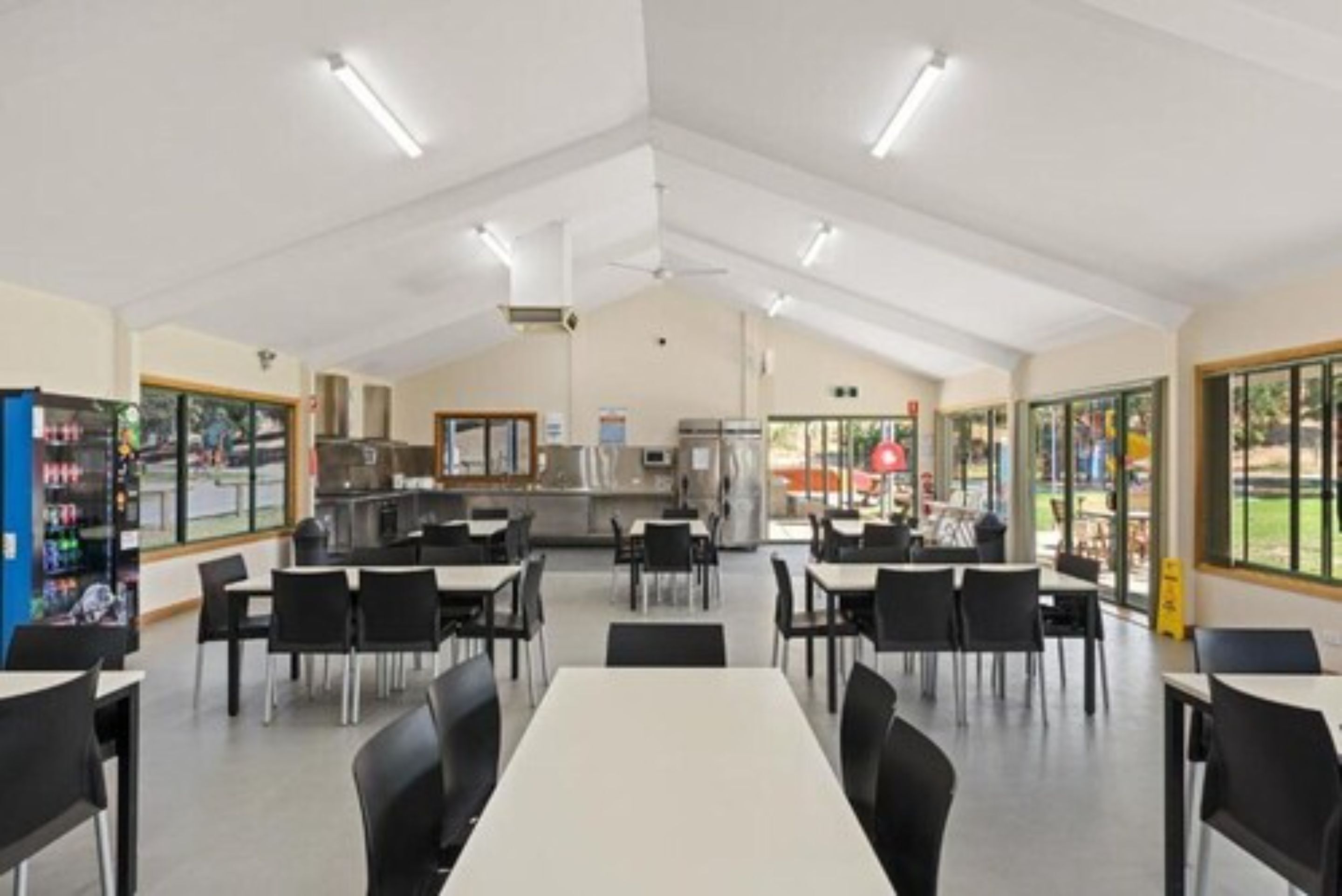 Un'ampia sala da pranzo interna con tavoli, sedie e una vetrina panoramica.