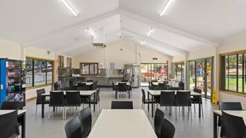 Un'ampia sala da pranzo interna con tavoli, sedie e una vetrina panoramica.
