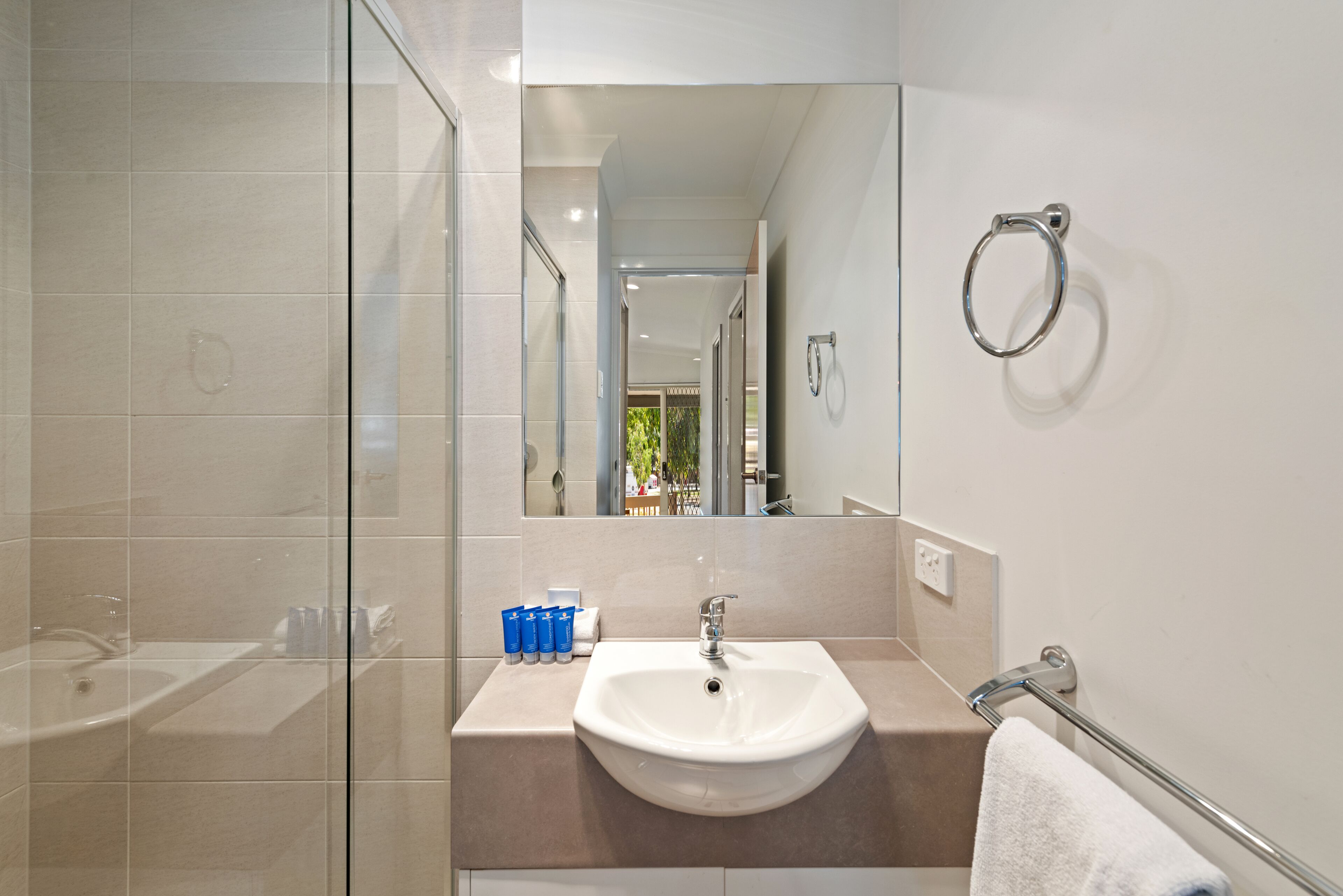 Un baño moderno con cabina de ducha de vidrio, un lavabo blanco y un espejo.