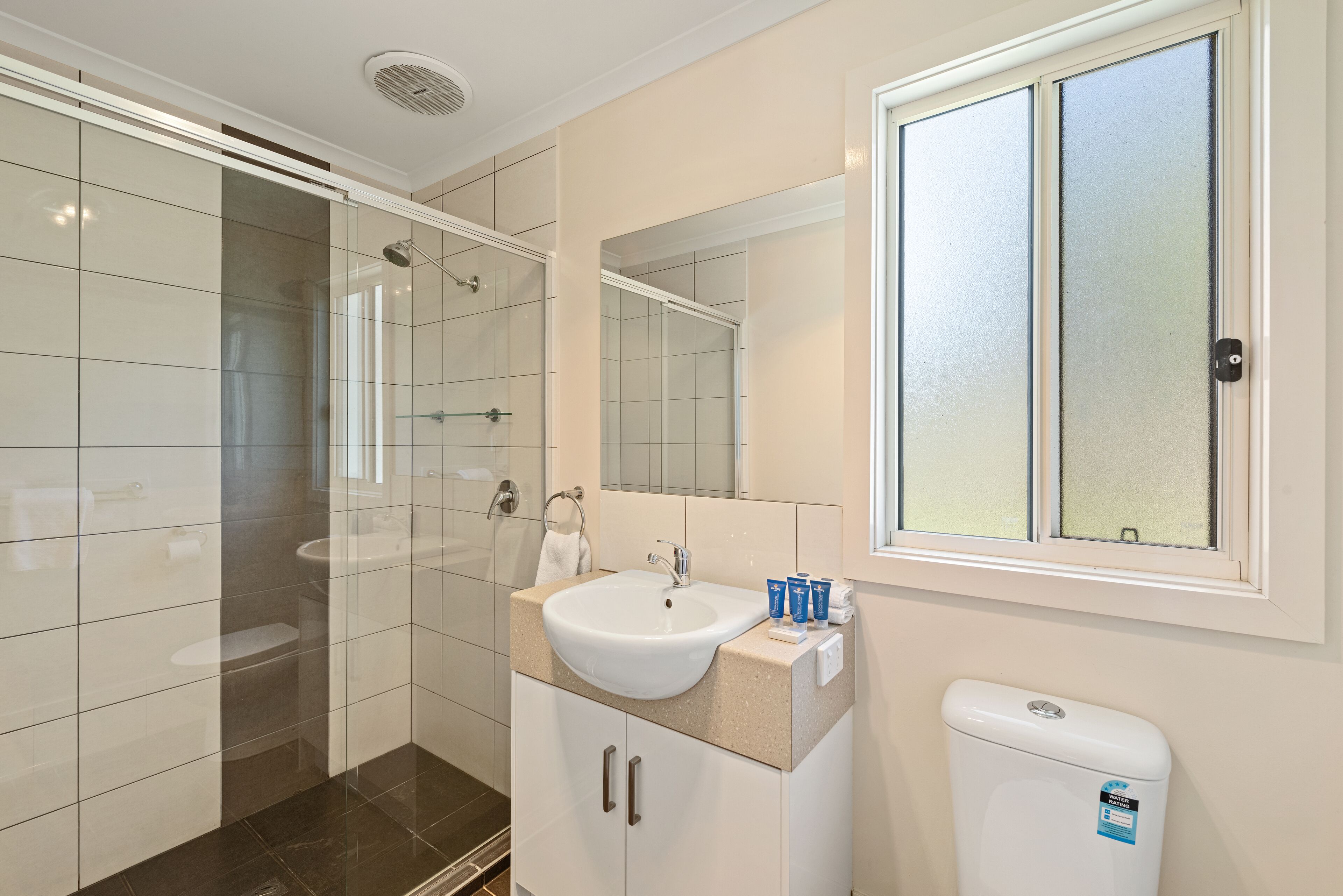 A modern bathroom with a glass shower enclosure, a white sink, and a toilet.