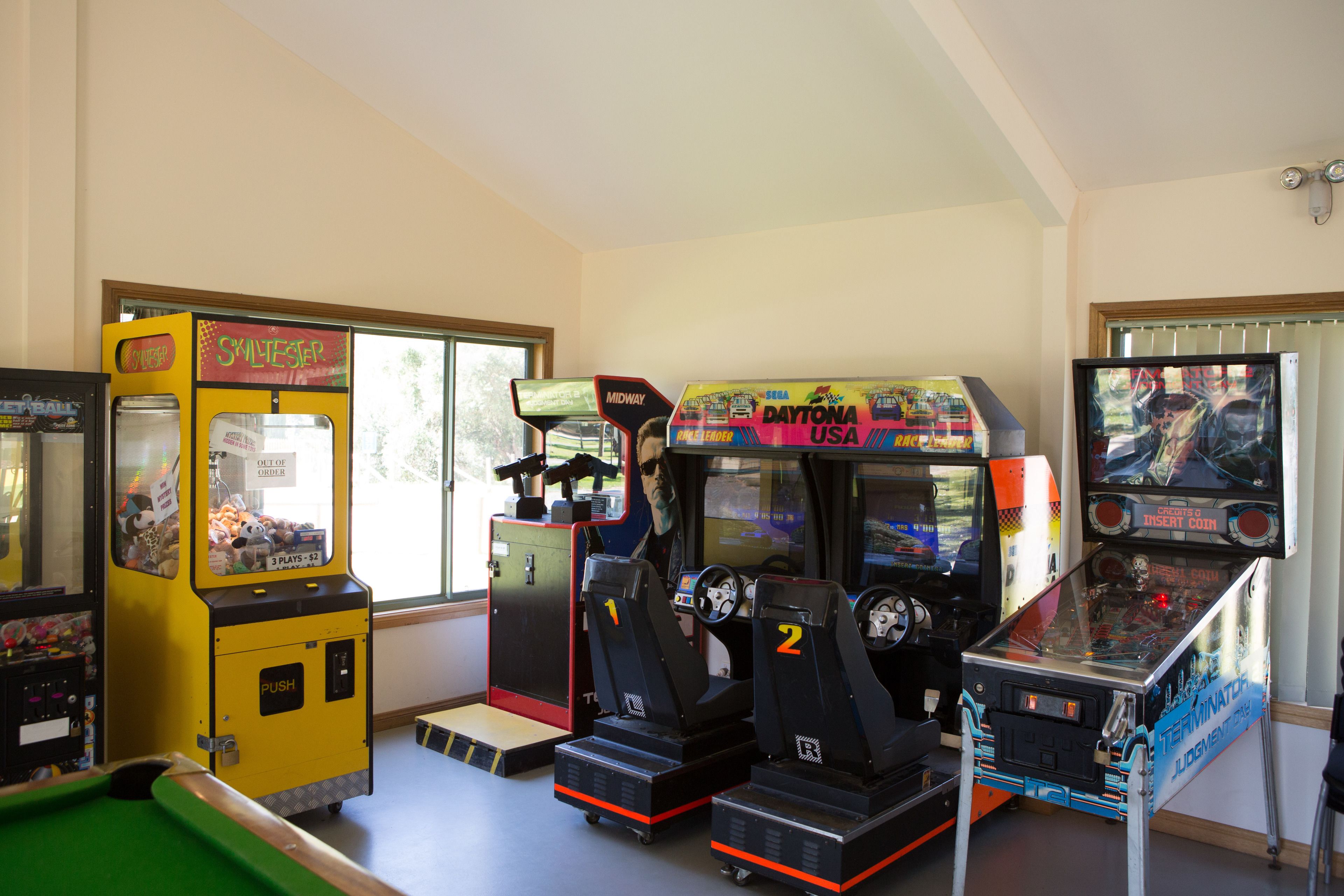A room with arcade games including 'Skilester' and 'Daytona USA'.