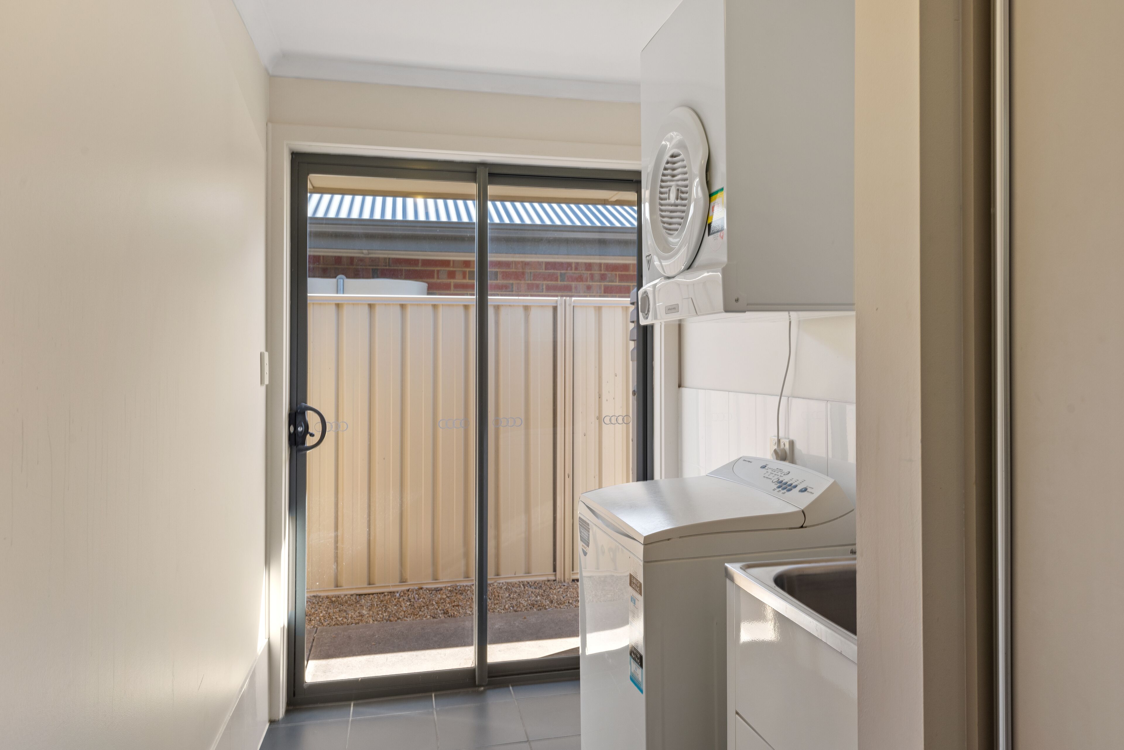 A laundry room with a washing machine, dryer, and a door leading to a balcony with a view of a brick building.