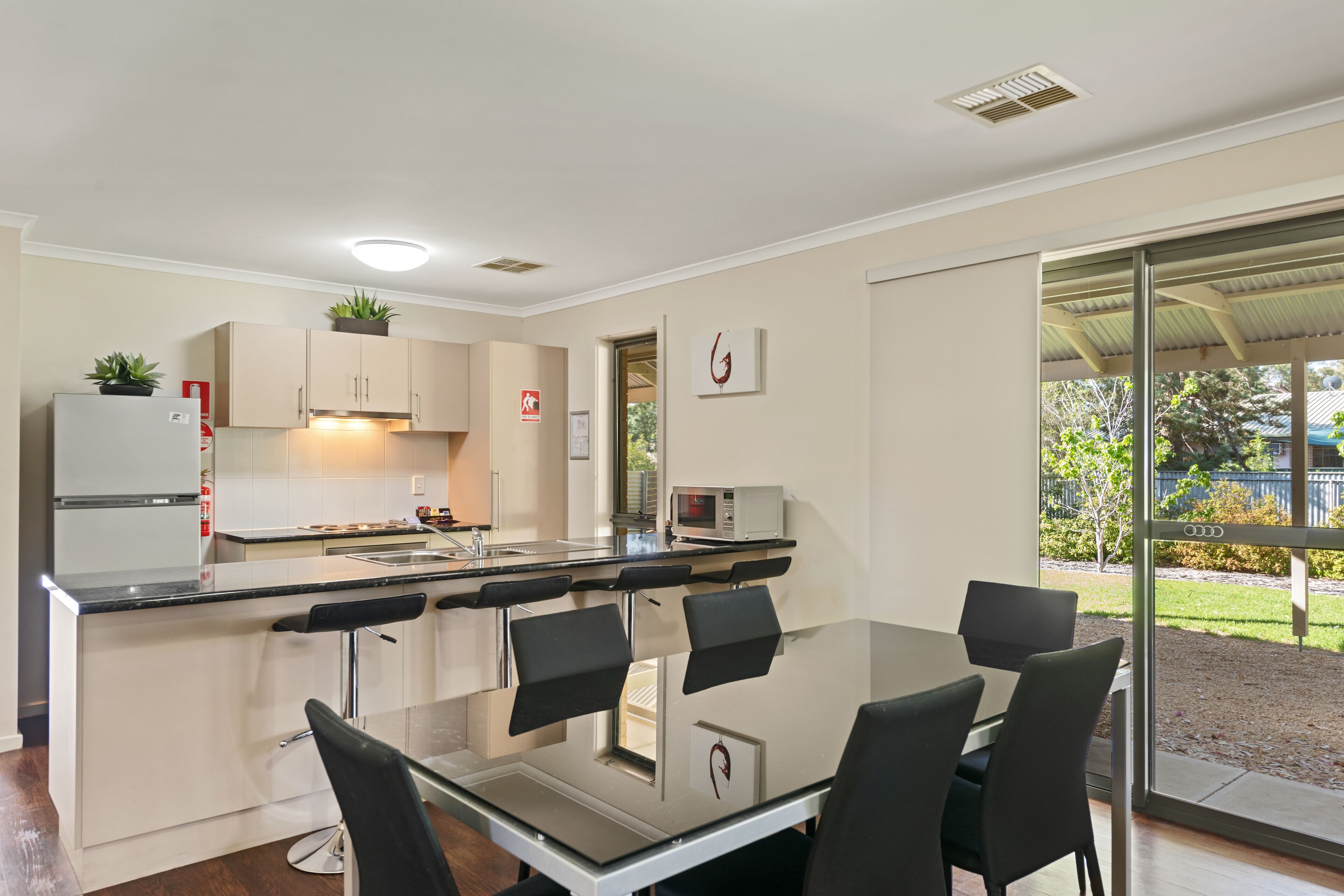 A modern kitchen with a central island, bar stools, and a dining table with chairs.