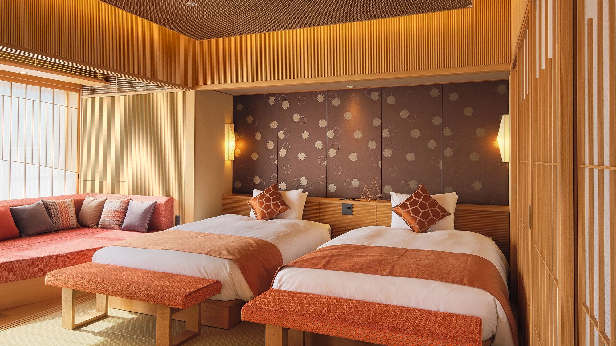 A hotel room with two beds, a seating area, and a decorative wall.