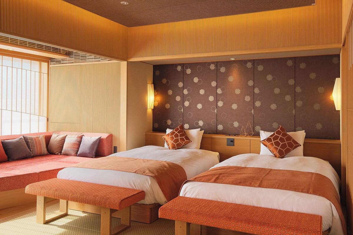 A hotel room with two beds, a seating area, and a decorative wall.