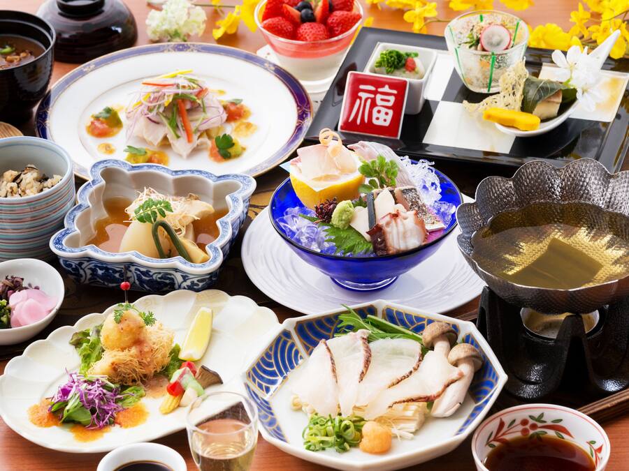 A variety of dishes on a table, including sushi, sashimi, and other Asian cuisine.