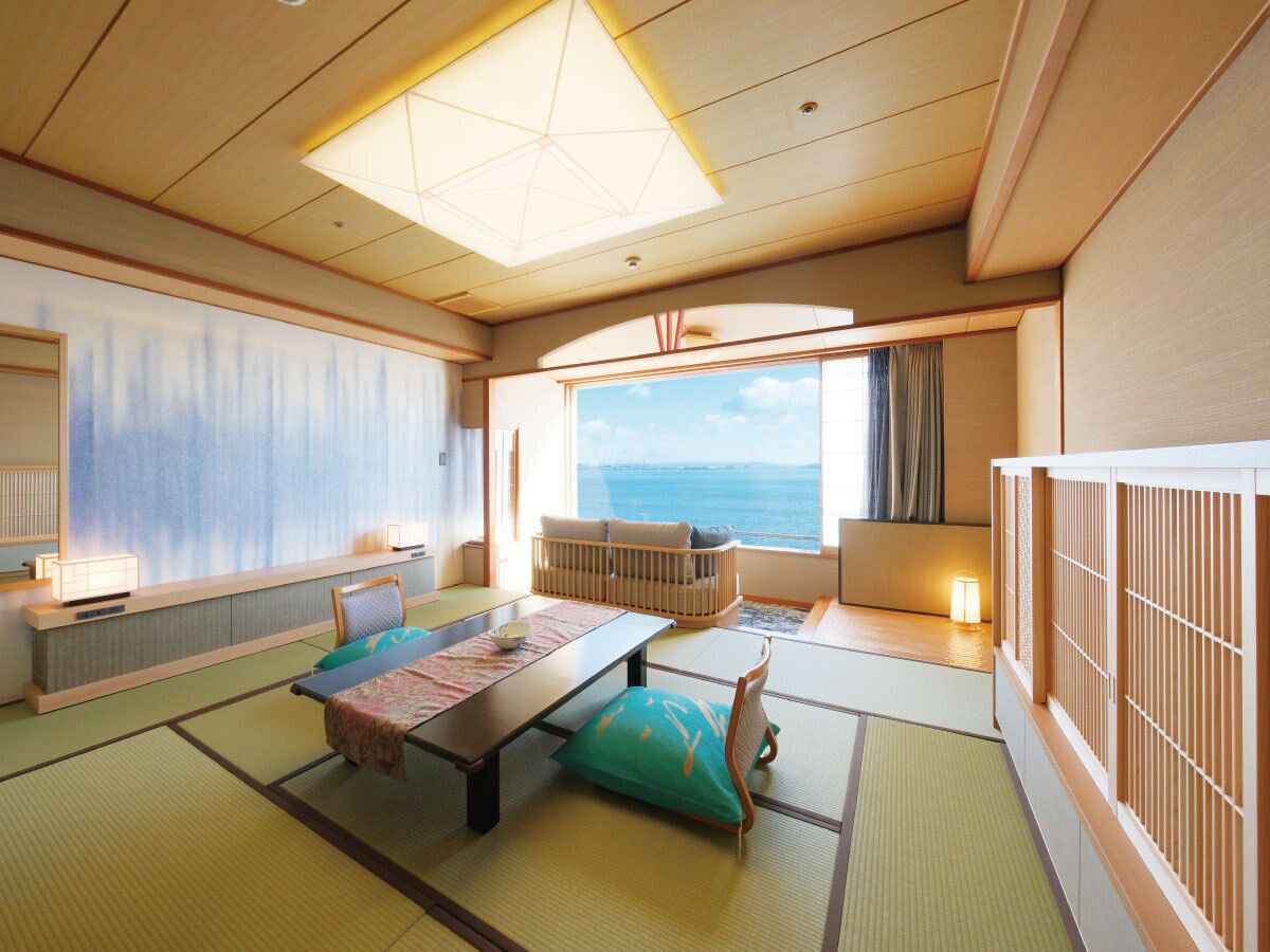 Una habitación japonesa tradicional con suelo de tatami, una mesa baja, cojines y vistas al mar.