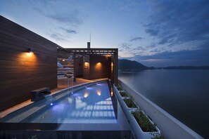 A modern outdoor pool area with wooden walls and a view of the water. - Hotel Ofutei (Fukuyama)