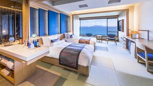 A modern hotel room with a large bed, a desk, and a view of the sea. - Hotel Ofutei (Fukuyama)